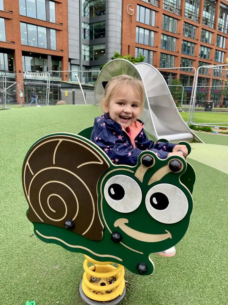 Young child playing in Manchester's Piccadilly Gardens.